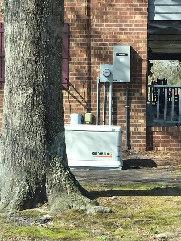 Generac standby generator installed beside a brick home