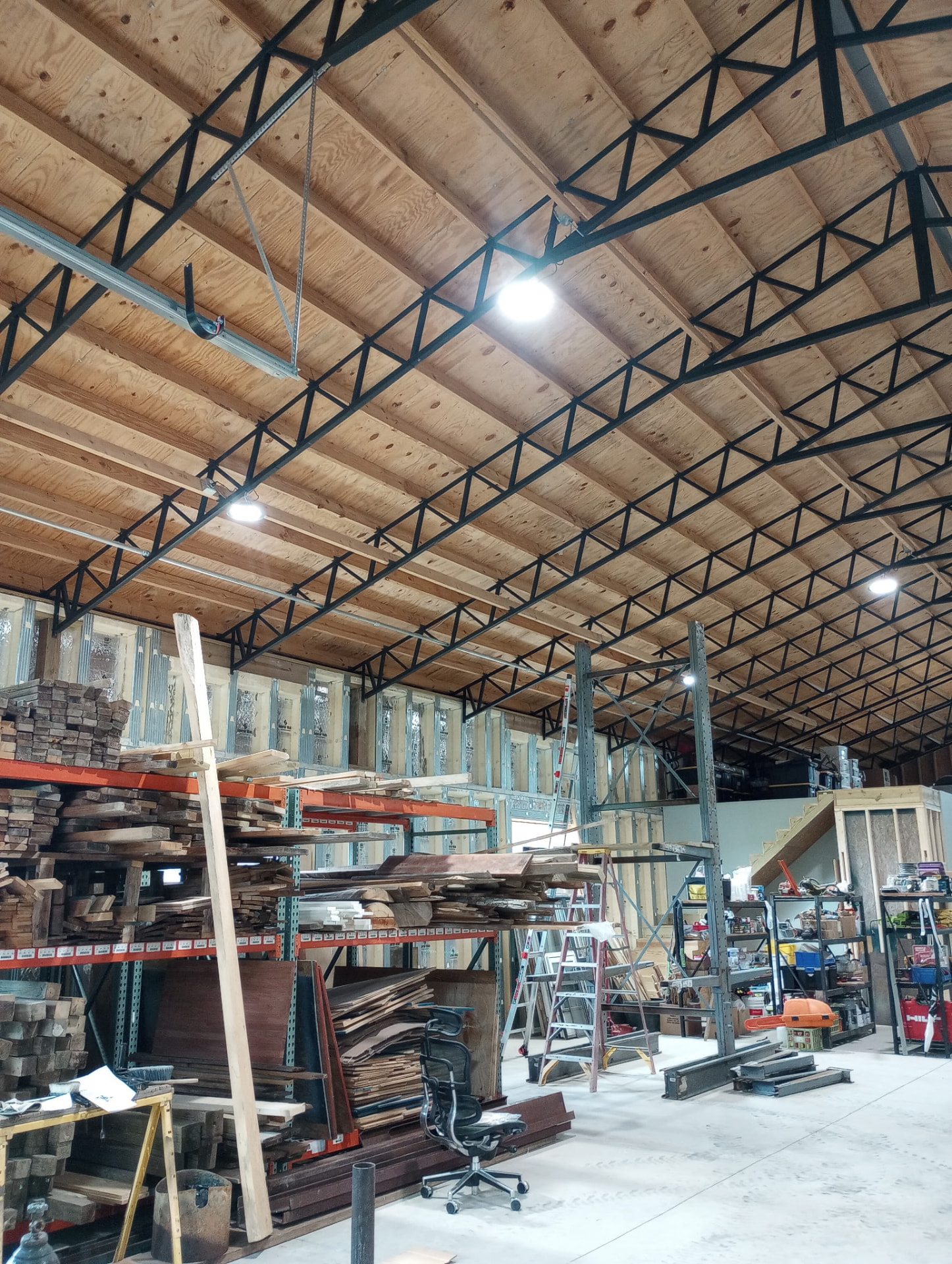 Warehouse interior with LED high bay lighting mounted to open trusses