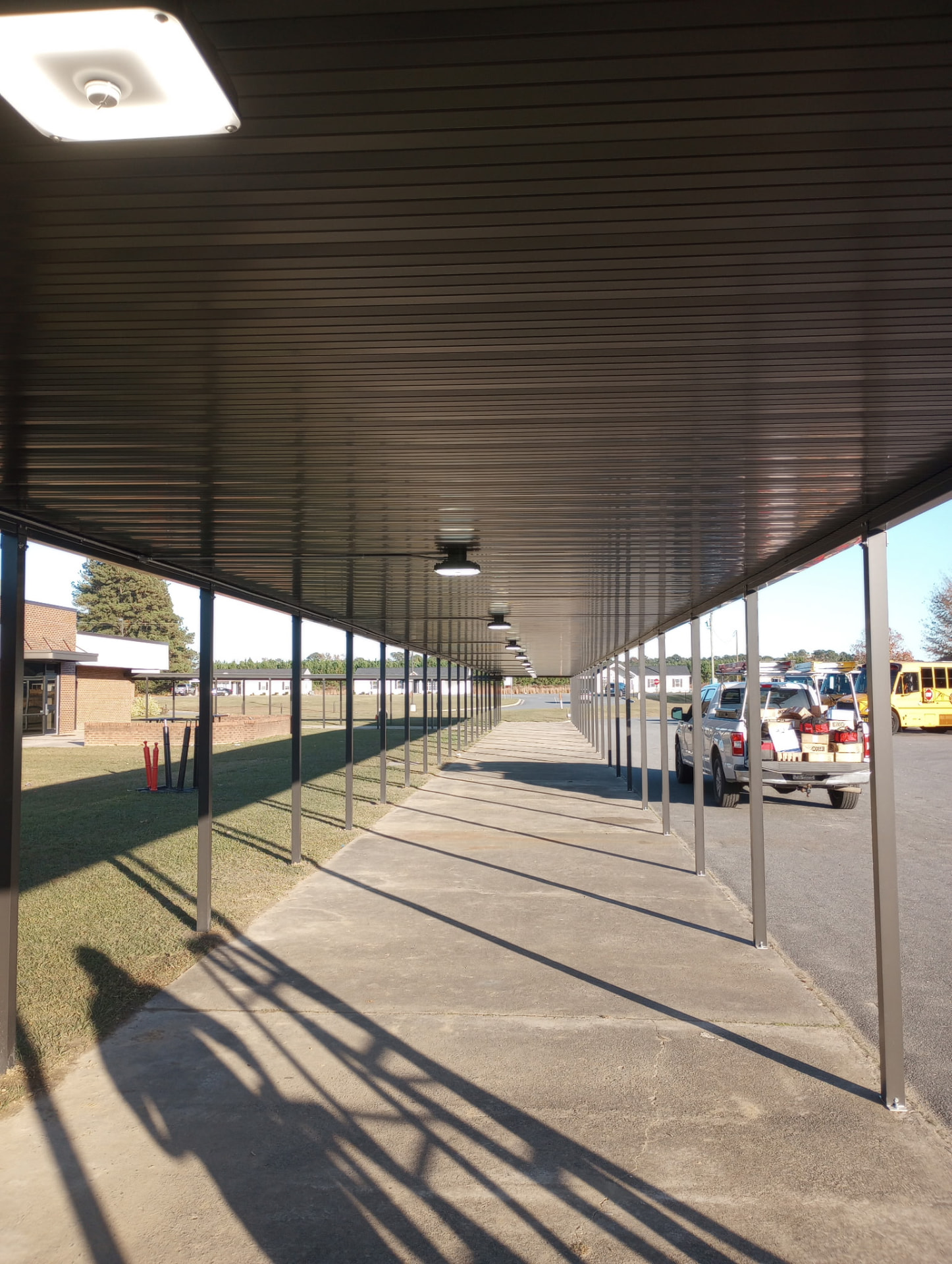 Covered breezeway with ceiling light fixtures installed along the walkway